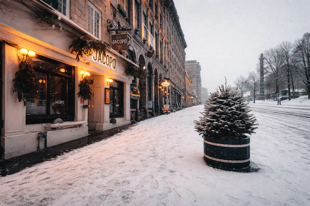 شارع في مونتريال شتاءً مغطى بالثلوج مع مبانٍ تاريخية وطقس غائم يعكس تحديات العيش في المدينة